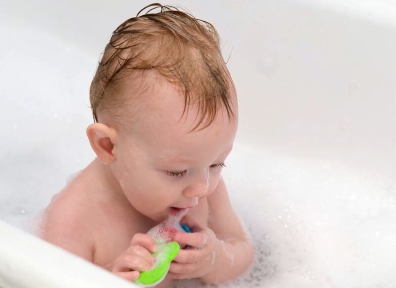 beba sedi u kadi sa vodom i igra se sa igračkom