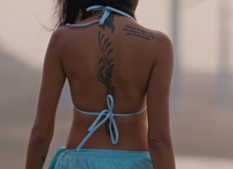 prikaz žene sa tetovažom na ramenu i leđima